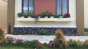 Une maison avec un balcon, des marches en pierre et des parterres de fleurs.