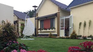 Une maison d’habitation avec une pelouse bien entretenue, une décoration en forme de voile suspendu et une variété de plantes à fleurs.