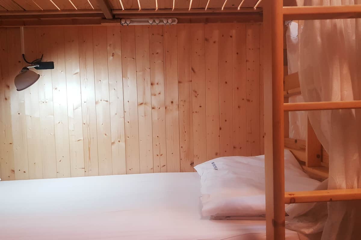 A bunk bed with a wooden headboard and a small desk lamp.