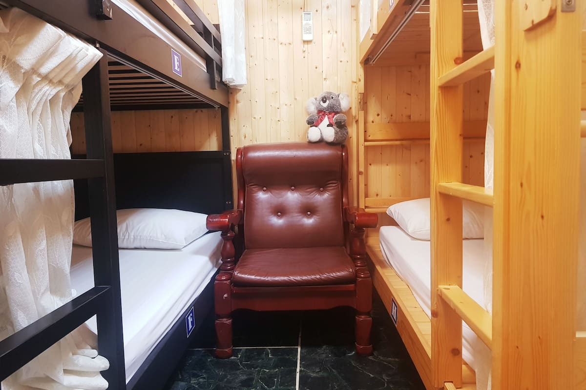 A compact room with bunk beds, a wooden chair, and a small shelf.