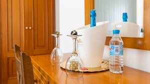 A wooden table with a water bottle, two wine glasses, and a white box with a blue logo. - Hotel Panadeiramar (Sanxenxo)