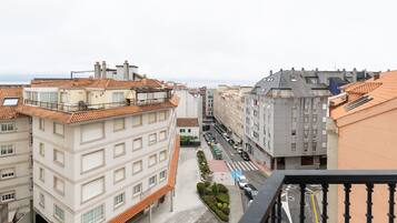Ein mehrgeschossiges Gebäude mit Ziegeldach, Innenhof mit Grünflächen und Blick auf die Straße.