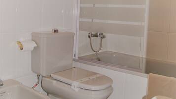 Un baño con inodoro, bidé y bañera.