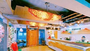 A modern hotel lobby with a wooden reception desk, a seating area with a table and chairs, and a decorative wall with floral arrangements. - Artch Inn (Luodong)