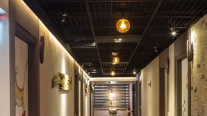 A hallway with a wooden floor, a fire extinguisher, and a wall with a newspaper article. - Artch Inn (Luodong)