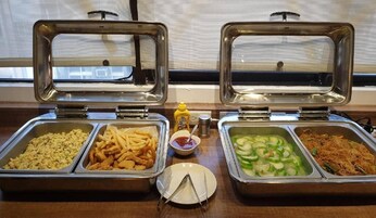 Un bufé con diferentes opciones de comida, como huevos revueltos, papas fritas y fideos.