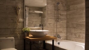 A modern bathroom with a wooden vanity, a large vessel sink, a handheld showerhead, and a toilet. - Artch Inn (Luodong)