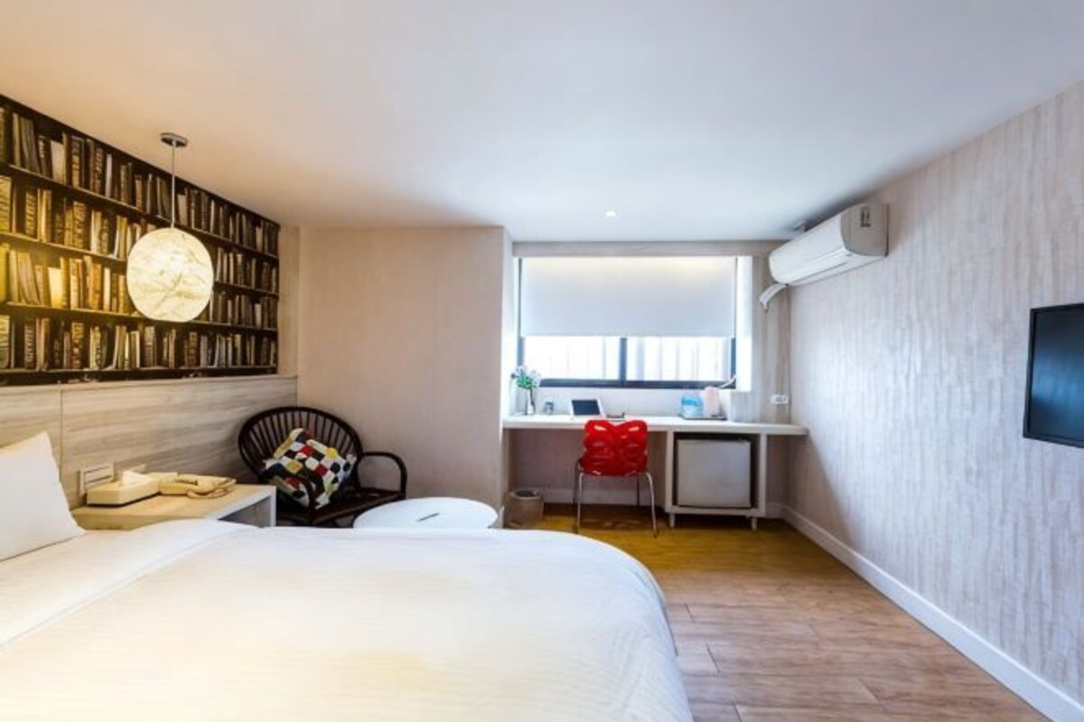 A bedroom with a bed, a desk, a chair, a bookshelf, and a window.