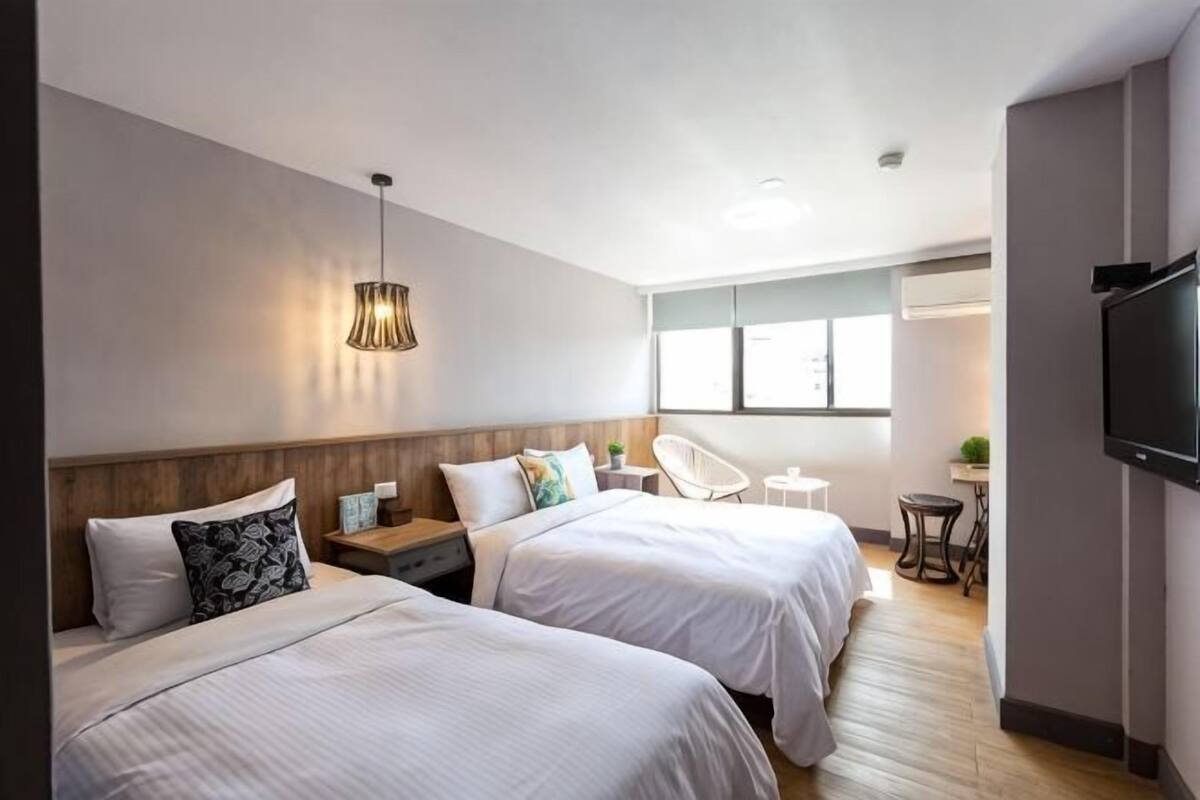 Quarto de hotel com duas camas, televisão, escrivaninha e uma cadeira.