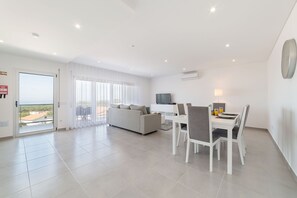 Un salon moderne comprenant un canapé, une table à manger et des chaises, un téléviseur et un balcon avec vue.