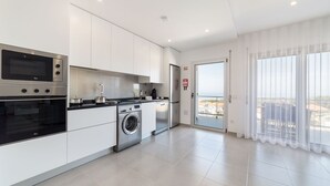 Een moderne keuken met een inbouwoven, magnetron en wasmachine.