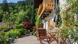 A courtyard with a wooden deck, outdoor seating, and potted plants.