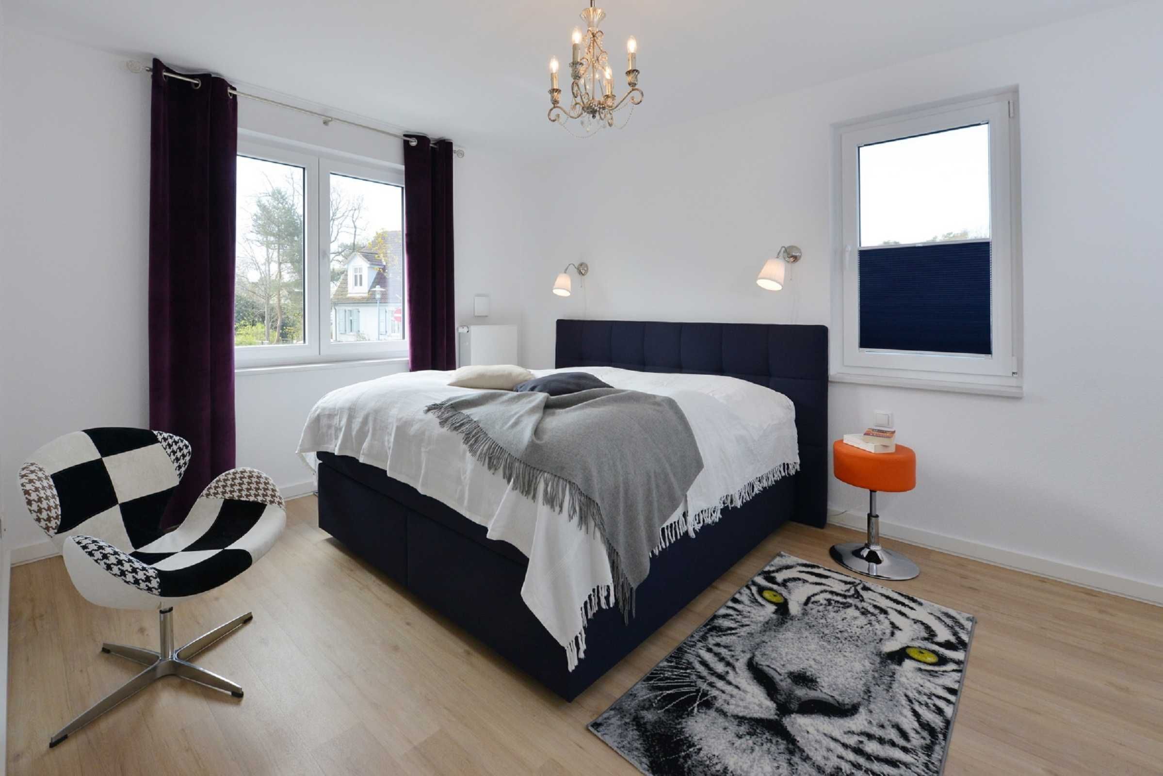 Un dormitorio con cama, una silla, una alfombra y una ventana.