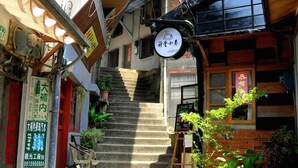 Un estrecho callejón con una escalera que lleva a un edificio con un letrero.
