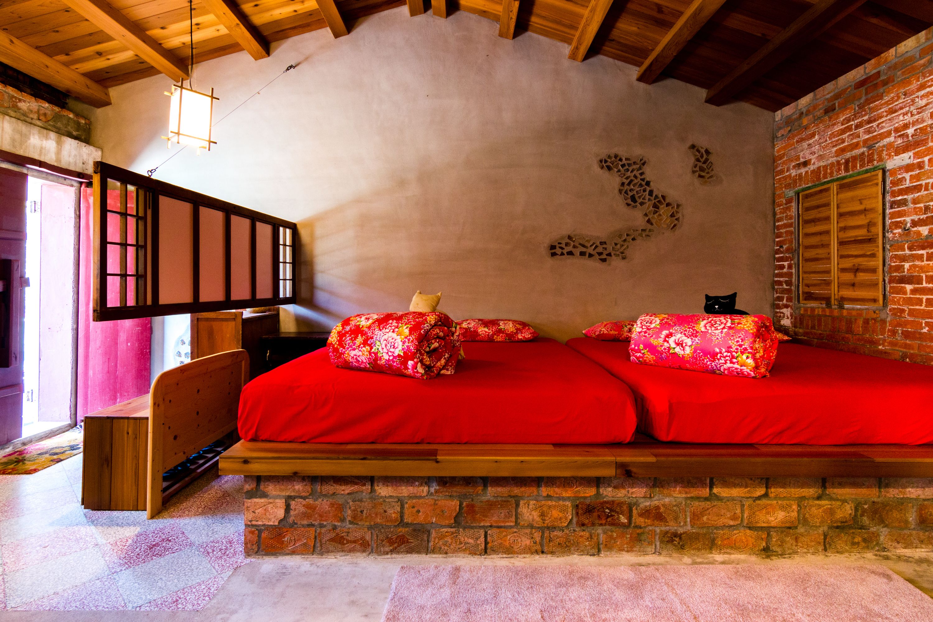 A cozy room with a wooden bed, a brick wall, and a wooden ceiling.