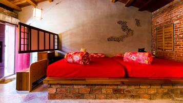 A cozy room with a wooden bed, a brick wall, and a wooden ceiling.