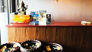 A reception desk with a statue, brochures, and a wall-mounted light fixture. - Tonle Khmer Guesthouse (Phnom Penh)