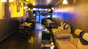 A restaurant interior with tables and sofas, a counter, and a view of the street outside. - Tonle Khmer Guesthouse (Phnom Penh)
