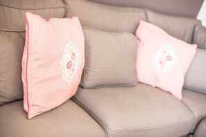 A beige sofa with two pink pillows with floral embroidery.