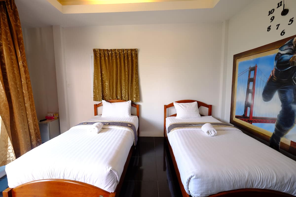 A hotel room with two single beds, a painting of the Golden Gate Bridge, a clock on the wall, and a curtain.