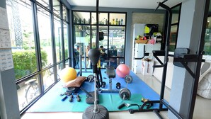 A gym with exercise equipment, large windows, and a view of the outside.