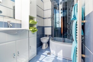 Un baño moderno con ducha de vidrio, inodoro blanco y lavamanos con espejo.