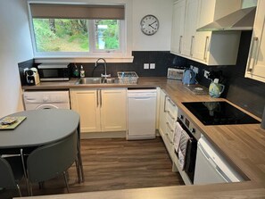 A compact kitchen with a microwave, toaster, sink, and dishwasher. - Loch Eyre Cottage (Skeabost)