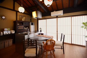 A traditional Japanese-style dining area with a wooden table, chairs, and a large window with shoji screens.