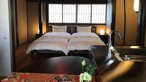 A traditional Japanese-style room with two beds, a wooden table, and a sink. - Kyo-Machiya YululY (Kyoto)