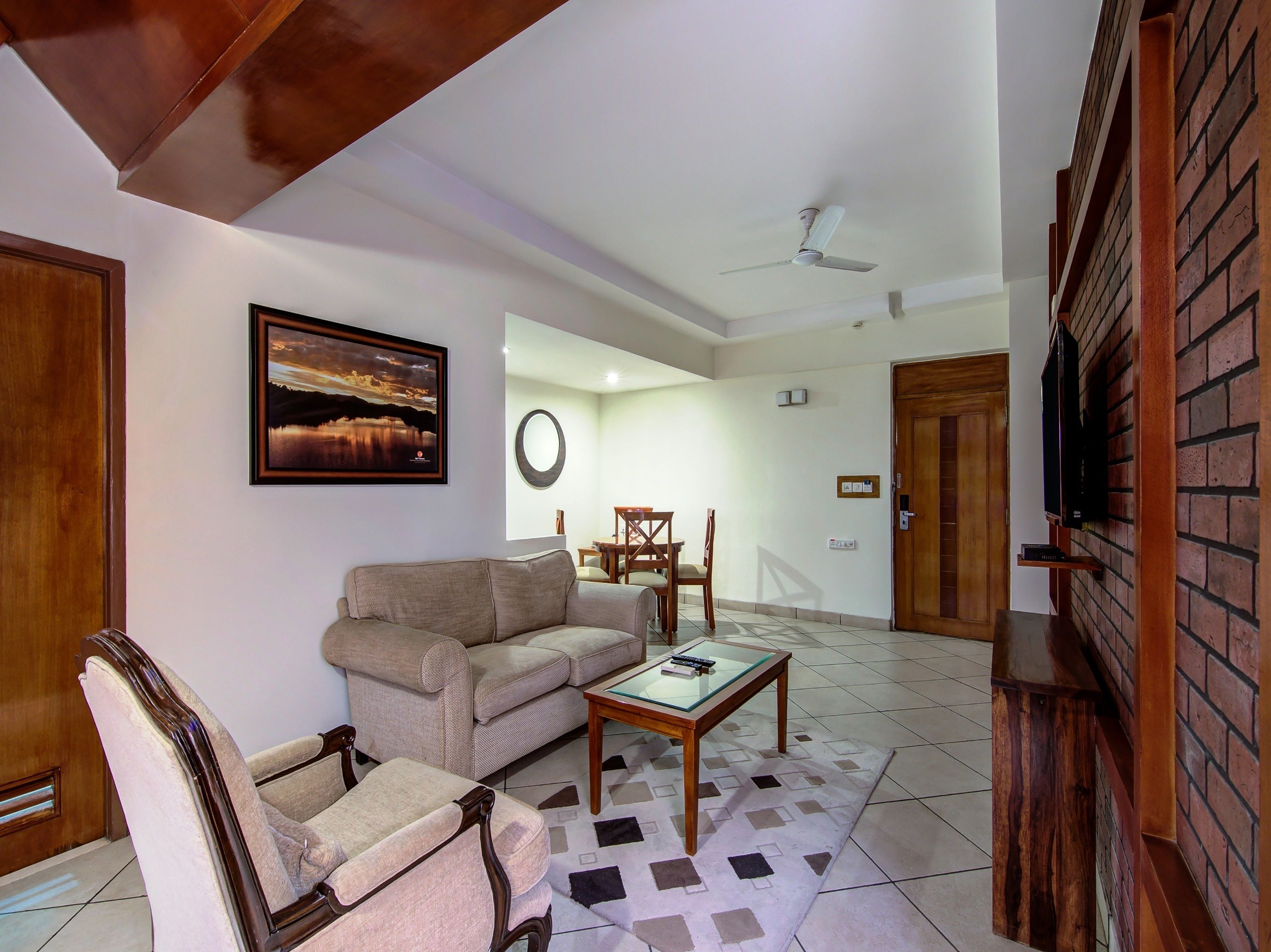 Una sala de estar con sofá, sillón, mesa de centro y un cuadro en la pared.