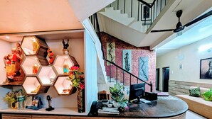 Una moderna zona de recepción con un mostrador curvo de madera, lámparas hexagonales e una escalera con barandilla de metal.