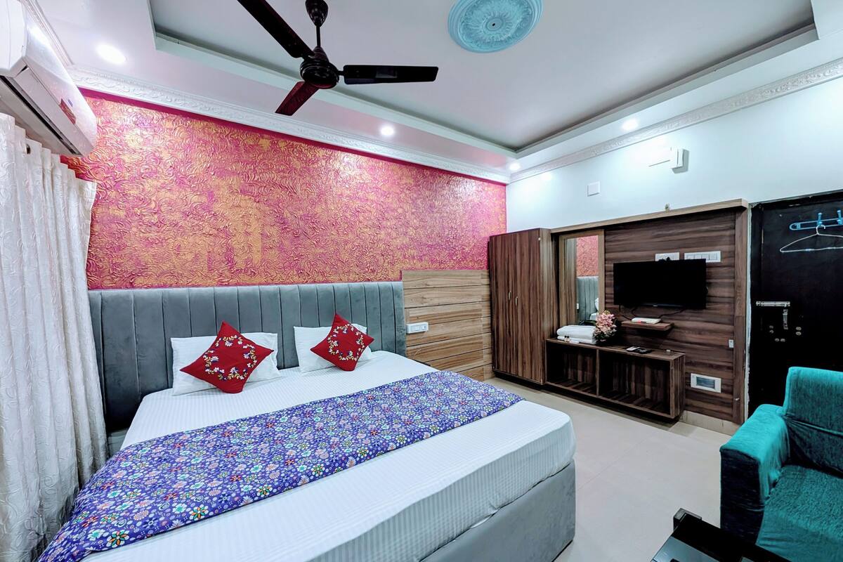 A modern bedroom with a large bed, a ceiling fan, a TV, and a wardrobe.