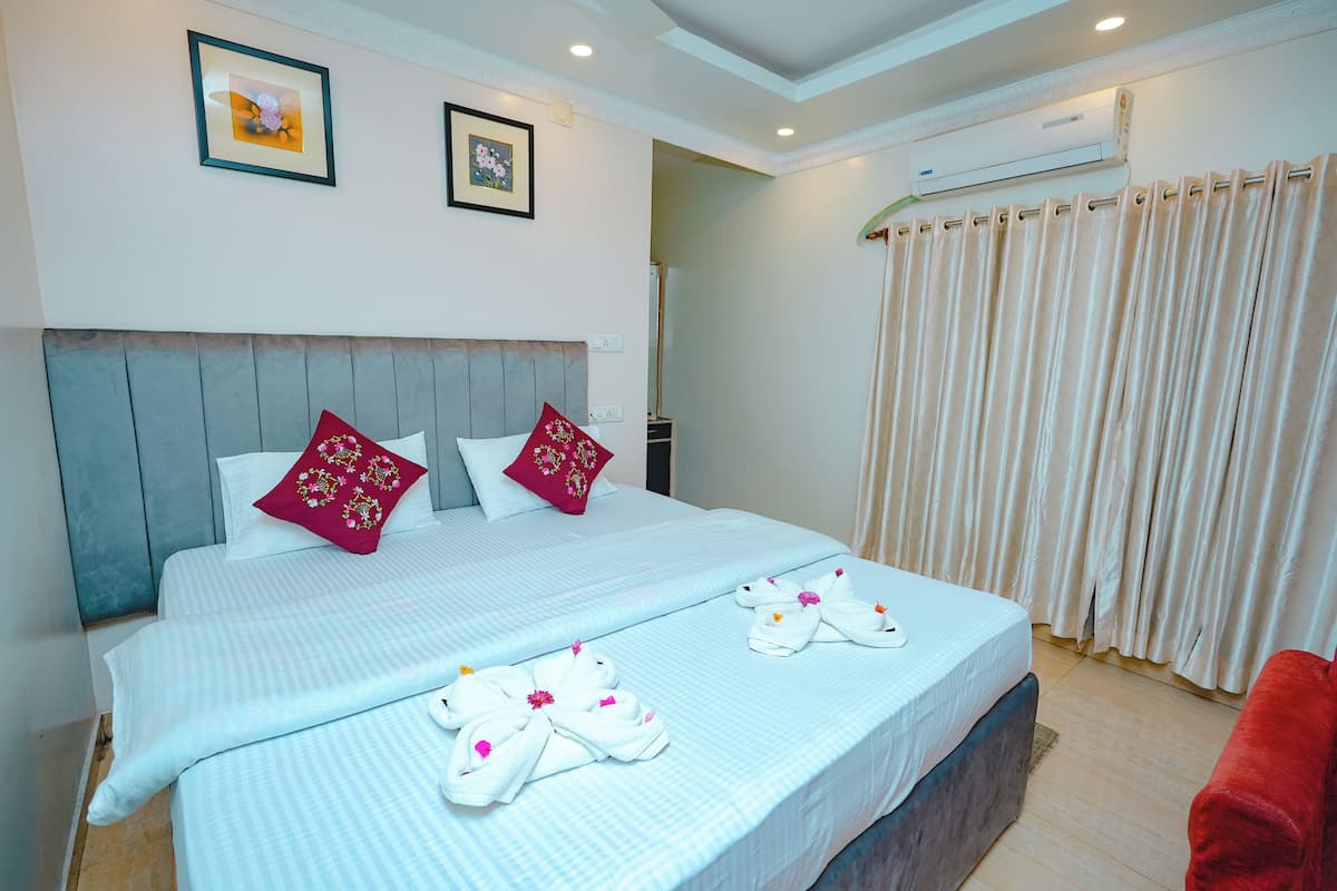 A hotel room with a large bed, two pillows, a headboard, a red chair, and a curtain.