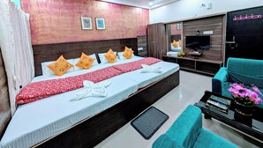 Una habitación de hotel moderna con una cama grande, un televisor, un armario y una zona de estar con una mesa y sillas.