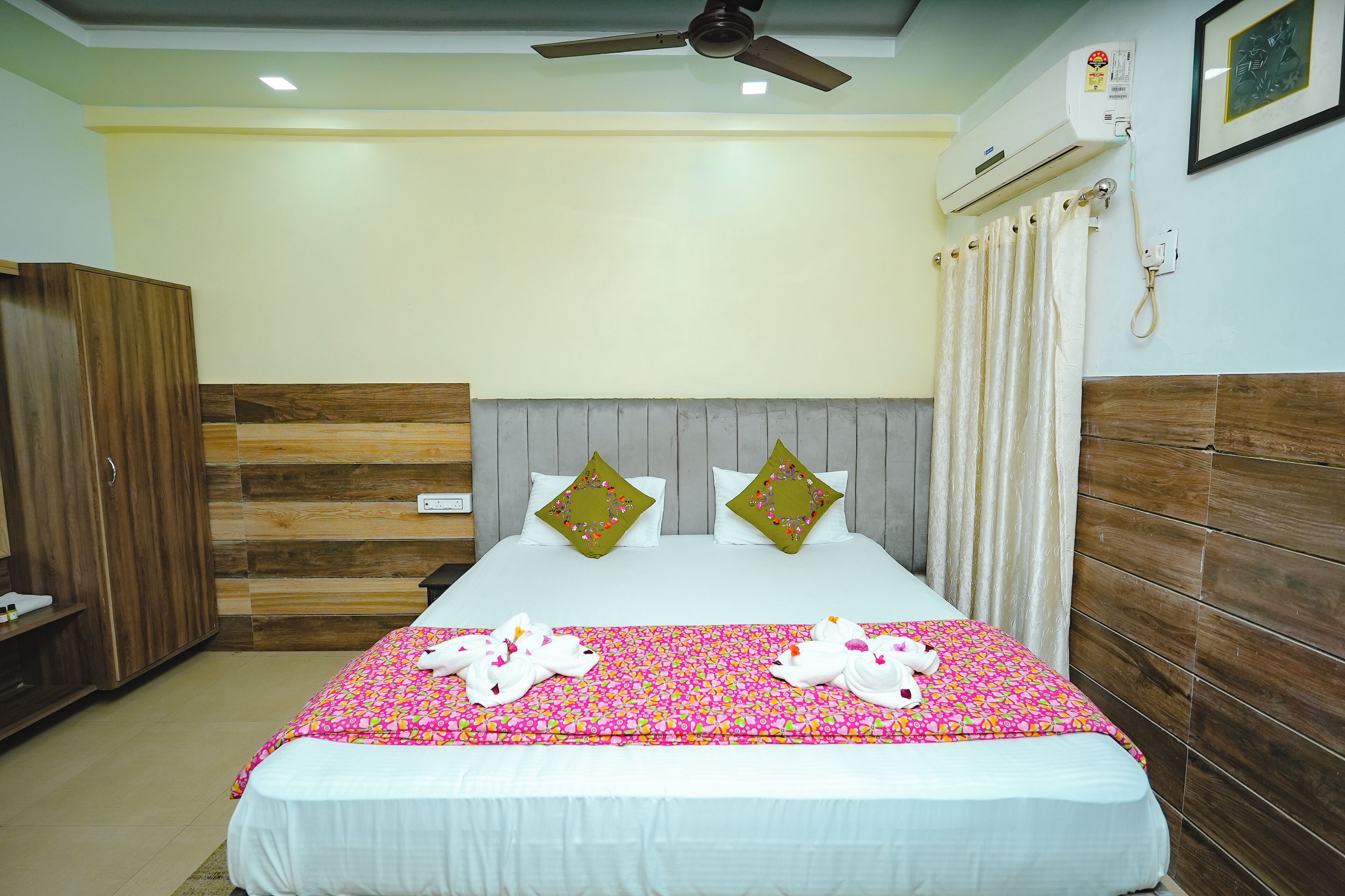 A hotel room with a bed, a wardrobe, a ceiling fan, an air conditioning unit, and a shower curtain.