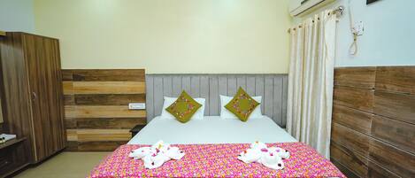 A hotel room with a bed, a wardrobe, a ceiling fan, an air conditioning unit, and a shower curtain.