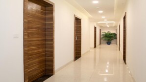 A hallway with wooden doors and a potted plant. - Hotel Narayanam (Kota)