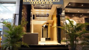 The entrance of Narayanan Hotel with a modern design, featuring a glass facade, a central staircase, and potted plants. - Hotel Narayanam (Kota)