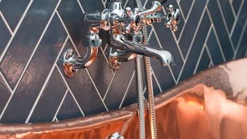 A bathroom with a modern, chrome faucet and a herringbone-patterned wall.