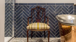 A chair with a striped cushion in a room with patterned tile walls and floor. - The Cornish Arms (Tavistock)