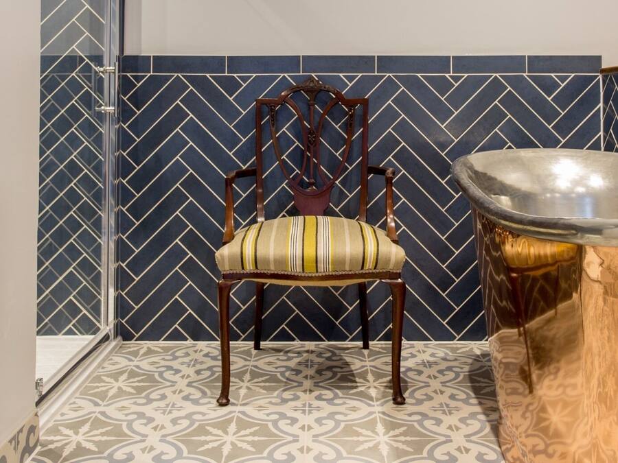 A chair with a striped cushion in a room with patterned tile walls and floor.