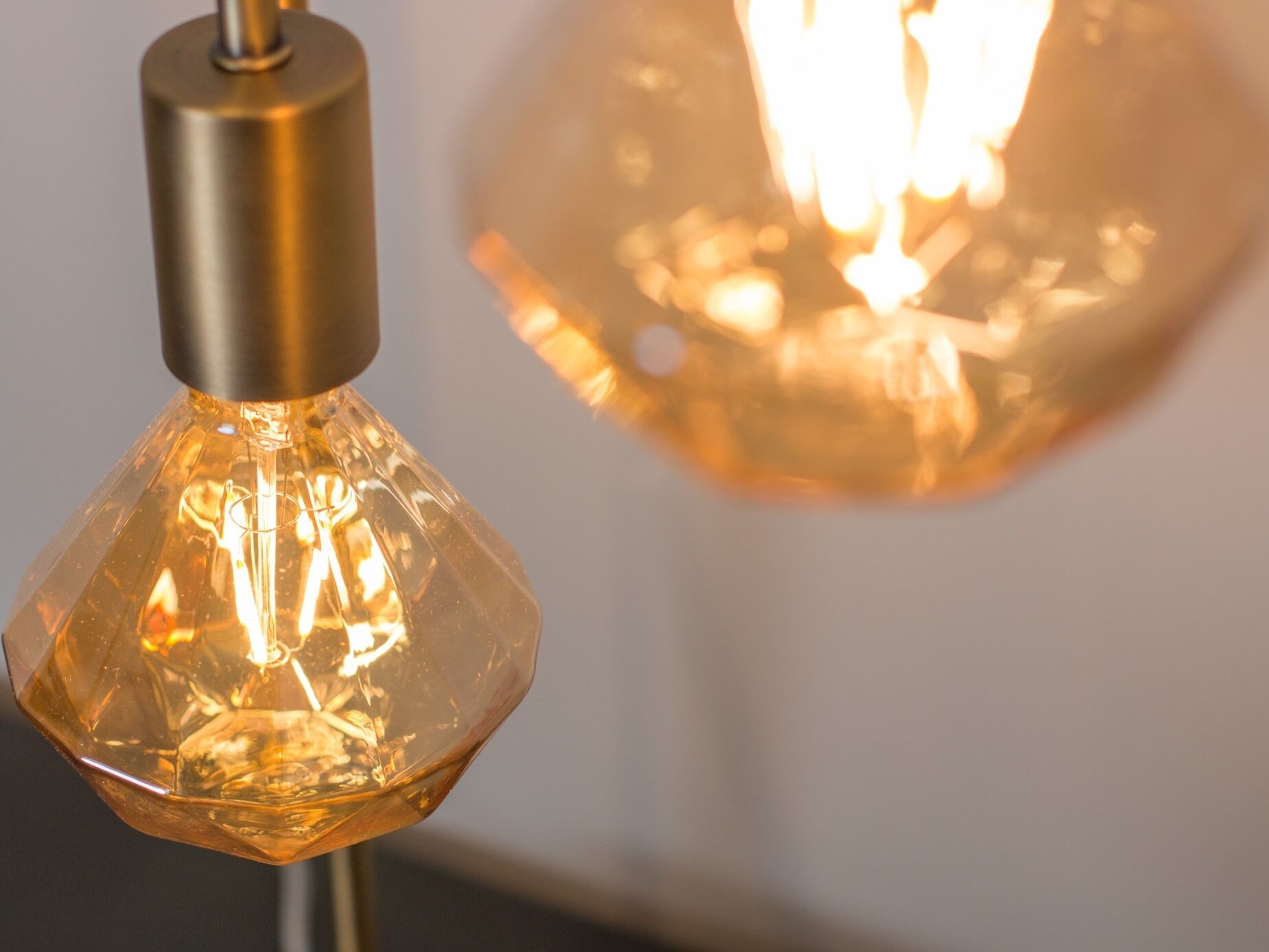 A close-up of a metallic light fixture with a glass shade, reflecting light.