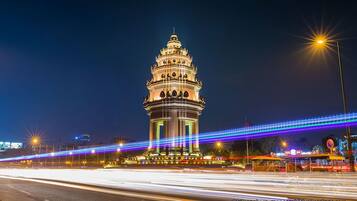 Una torre bien iluminada de diseño tradicional, rodeada por un puente moderno con iluminación.