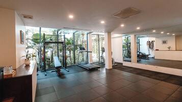 Un gimnasio con cinta de correr, máquinas de pesas y un muro de espejos.