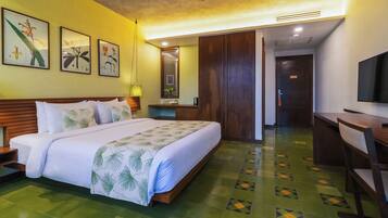 A hotel room with a large bed, a desk, a television, and artwork on the wall.