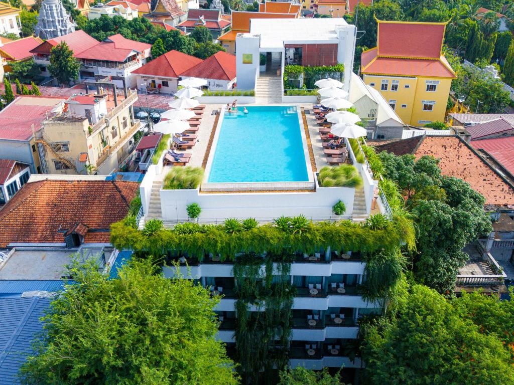 Una piscina en la azotea con sillones de descanso y sombrillas, rodeada de vegetación y arquitectura tradicional.