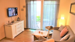 Ein Wohnzimmer mit Fernseher, einer Couch, einem kleinen Tisch und einem Schrank.