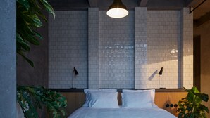 A bedroom with a bed, white walls, and a hanging light fixture. - The Emerald (Prague)