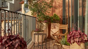 A wooden deck with potted plants, a folding chair, and a small table. - The Emerald (Prague)
