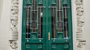 A green double door with intricate metalwork and a decorative archway. - The Emerald (Prague)